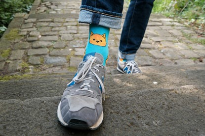 Person wearing bright cat socks and trainers