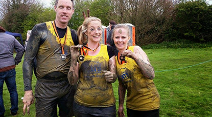 two women and one man in muddy Cats Protection vests