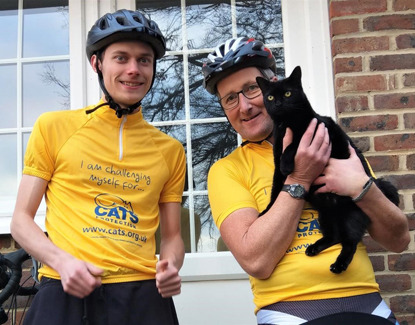 Cyclists in Cats Protection tops holding black cat