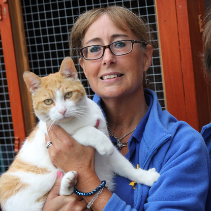 Cats Protection volunteer holding ginger and white cat
