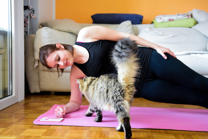 lady doing yoga on pink mat with tabby cat