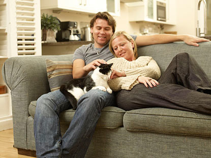 man and woman on sofa with black and white cat