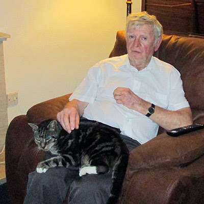 older man sitting with tabby cat on his lap