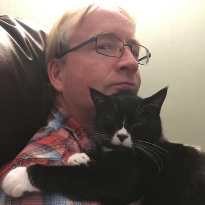 black and white cat sleeping on man's chest