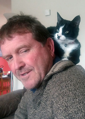 black and white cat sitting on man's shoulder