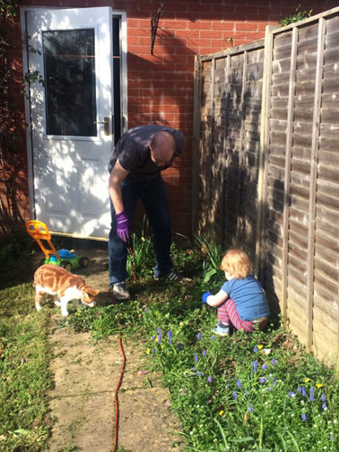 man gardening with toddler and ginger cat