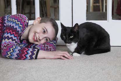 young girl lying on floor with a black and white cat