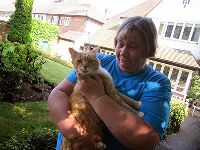 tearful woman holding ginger cat in garden