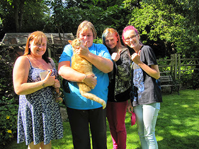 Ginger cat held by tearful woman in a garden