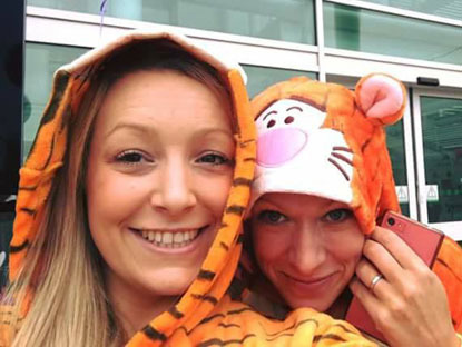 two blonde ladies wearing tiger onesies for selfie