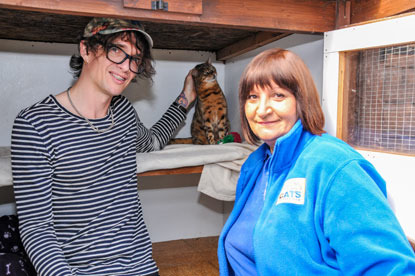 The Darkness frontman Justin Hawkins with his cat and a Cats Protection volunteer in a foster cat pen