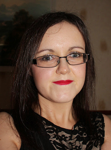 woman with brown hair, wearing glasses and red lipstick
