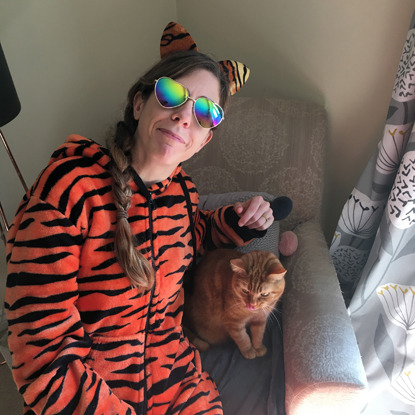 woman in tiger onesie with a ginger cat