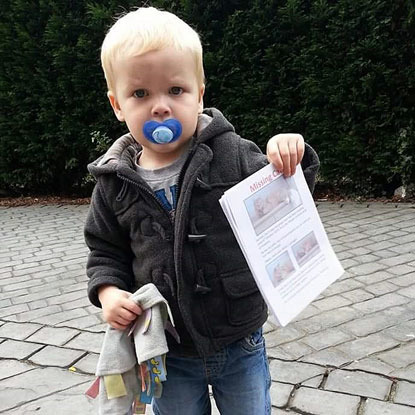 blonde toddler holding missing cat posters