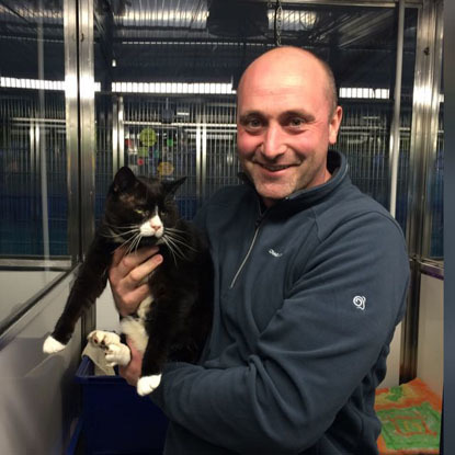 man in animal shelter holding black cat