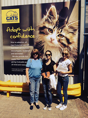 three women in front of Cats Protection banner