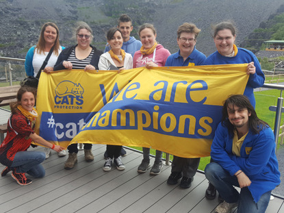 group of people holding Cats Protection Cat Champions banner