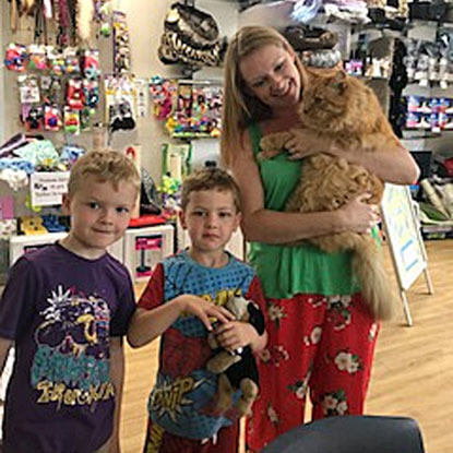 blonde woman and children with ginger cat in Cats Protection shop