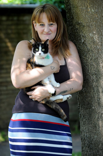 brunette woman holding black and white cat outside
