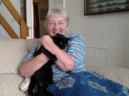 woman cuddling black cat on sofa