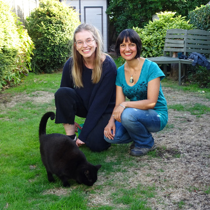 two women in garden with black cat
