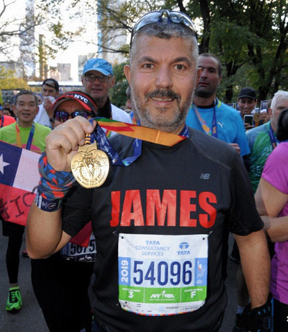 man wearing running top and holding marathon medal