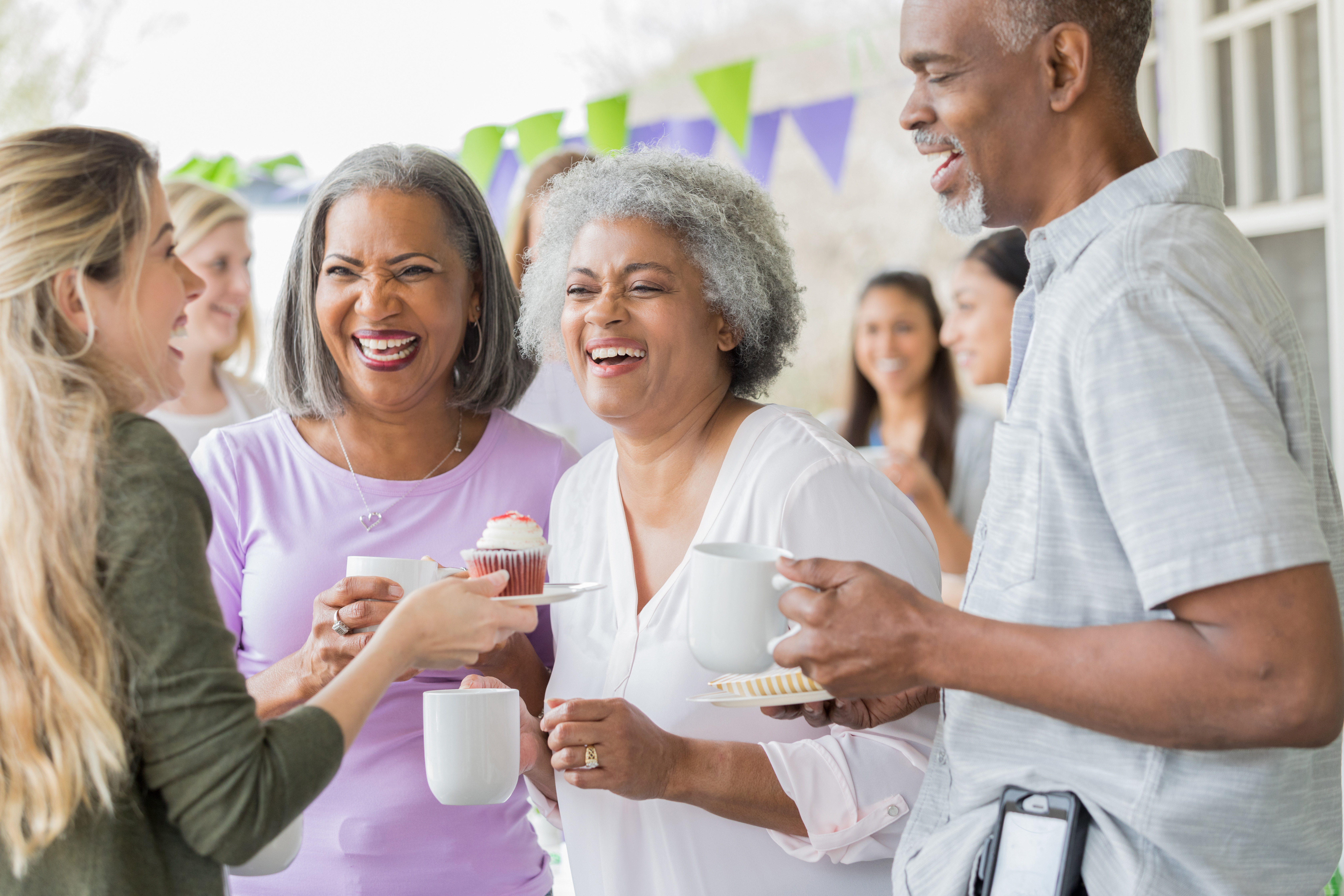 People laughing at an outdoor event with cup cakes.